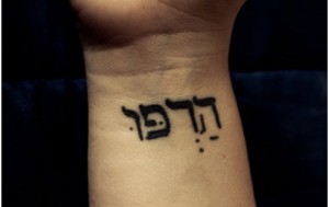 black-ink-hebrew-tattoo-on-left-wrist